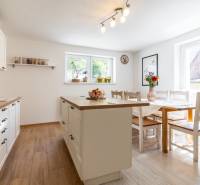 A kitchen in a family house with a table, an island, and accessories on a wooden floor.