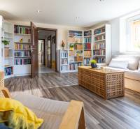 Living room in a family house with a library, light furniture, and plants.