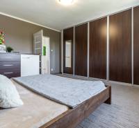 Bedroom with a bed, wardrobes on the wall, dresser with decorations, family house.