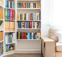 A bookshelf next to the sofa in the family house, a bright room with wooden flooring.