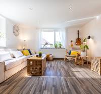 Bright living room with a sofa, a guitar on the wall, and wooden flooring. Family house.