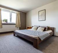 Bedroom with a wooden bed, wall decoration, and a window in a family house.