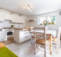 A kitchen in a family house with white cabinets, a wooden table, and cozy lighting.