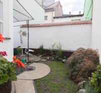 A small garden by a 2-room apartment with paving, plants, and stone decorations.