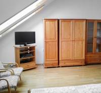 Skylight, wooden furniture, and a television in the living room of a two-room apartment.