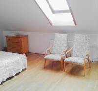 An attic room with two armchairs, a dresser, and a bed in a two-room apartment.