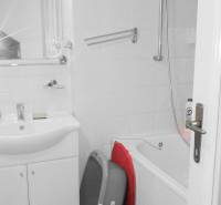 Bathroom in a 2-room apartment with a bathtub and a sink, white tiles.