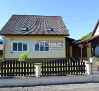 A family house in Župkov with a wooden fence and a satellite dish on a sunny plot.