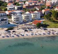 A beach with sunbeds and umbrellas, behind it houses and buildings in the resort.