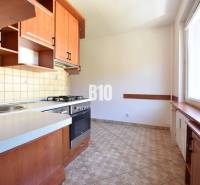 The kitchen of a 4-room apartment with a large window, wooden furniture, and tiles.