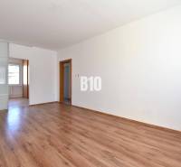 A spacious room with wooden flooring and sliding doors in a 4-room apartment.