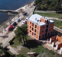 A building by the sea in the town of Vir with an access road and greenery.