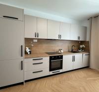 A kitchen in a 3-room apartment with a complete set of cabinets, a wooden countertop, and decorations.