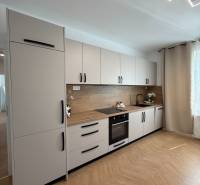 A kitchen in a 3-room apartment with white cabinets and an angled lighting setup.