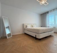A bedroom in a 3-room apartment with a comfortable bed, stylish mirror, and patterned floor.
