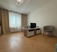 Living room in a 3-room apartment with a TV, an armchair, and a dining table. Simple furnishings.