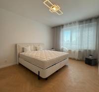 A bright bedroom with a large bed and a geometric light fixture in a three-room apartment.