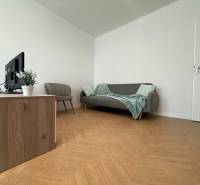Living room in a 3-room apartment with a sofa, armchair, and television on a wooden cabinet.