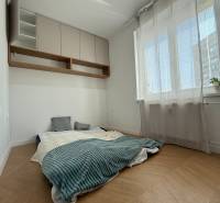 Bright bedroom in a 3-room apartment with a low bed and storage cabinets.