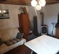 Living room in a cottage with a sofa, table, and wood stove.