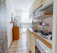 A narrow kitchen in a 3-room apartment with stone cladding and a stove.