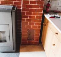 A family house with a brick fireplace, a stove, and a kitchen unit in wooden design.