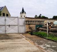 The entrance courtyard of a family house at 2473 Potzneusiedl with a gate and stacked wood.