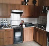 A kitchen in a family house with wooden cabinets and white tiles.