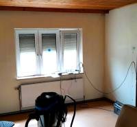 A room in a family house with a window, a radiator, and a wooden ceiling.