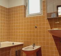 A bathroom with orange tiles in a family house, contains a bathtub, bidet, and sink.