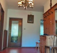 A hallway in a family house with wooden paneling, a mirror, and a decorative chandelier.