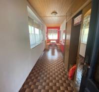A long hallway in a family house with a patterned floor and a wooden ceiling.