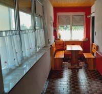 A family house with a wooden seating area in the kitchen, red walls, and a tiled floor.