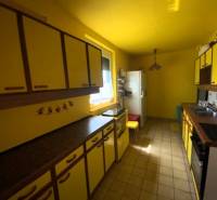 A kitchen in a family house with yellow walls and cabinets, the space is bright and functional.
