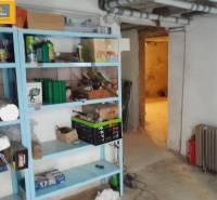 The basement of a family house with a shelf full of tools and pipes on the wall.