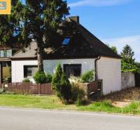A family house in Hundsheim with a white facade, wooden fence, and surrounding greenery.