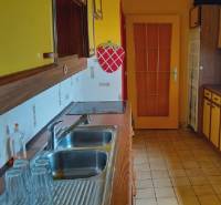 A kitchen in a family house with yellow cabinets and a stainless steel sink.