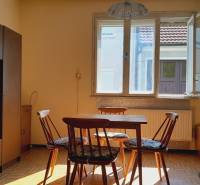 A room with a table and chairs lit by the sun, Apartment construction.