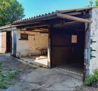 A tin garage with open doors, surrounded by greenery in Joise, Apartment construction.