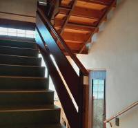 A staircase with wooden railing and carpeted steps within the construction of apartments.