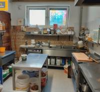 Kitchen in a gastro space with tables, containers, and cooking equipment.