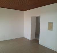 The interior of a commercial space with white walls, a brown ceiling, and tiles.