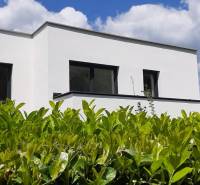 A villa in Hainburg an der Donau with a white facade, surrounded by greenery under a blue sky.