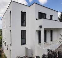 Villa in Hainburg an der Donau with a white facade, surrounded by greenery and a blue sky.
