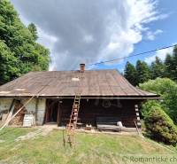A rustic cottage in Zákopčie surrounded by forests and a dramatic cloud in the sky.