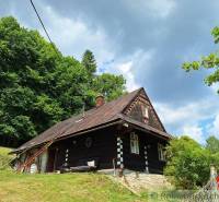 A cottage in Zákopčie surrounded by forests and beautiful nature under a cloudy sky.