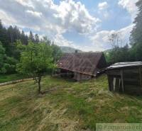 A wooden cottage in Zákopčie surrounded by forests and a blue sky.