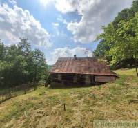 A cottage in Zákopčie surrounded by nature and forests under a blue sky.