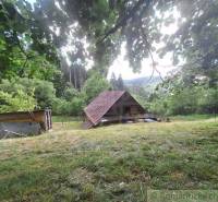 A cottage in Zákopčie surrounded by green nature and hills in the background.