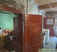A cabin with wooden walls, view of a room with a sofa and a kitchen.